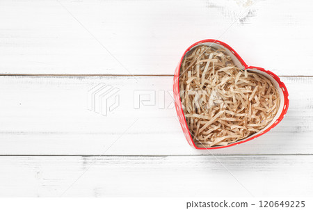 Heart-Shaped Box Filled with Shredded Paper on White Wooden Background 120649225