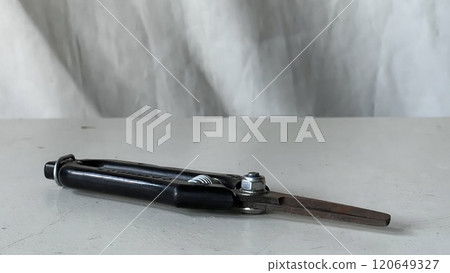 Metal compass resting on a white table with a textured background Metal compass resting on a white table with a textured background 120649327