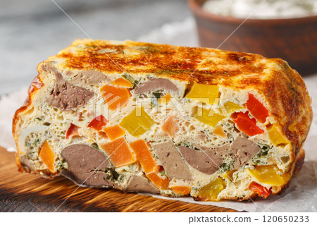 Liver casserole with vegetables, herbs and eggs close-up on a wooden board. Horizontal 120650233