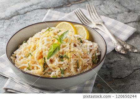 Italian spaghetti pasta with ricotta, lemon zest and juice, parmesan, pepper and basil close-up in a bowl. Horizontal 120650244