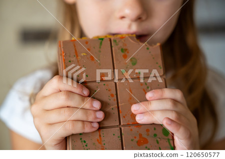 Dubai chocolate with pistachio paste and kataifi dough in hands of little girl. Confectionery handmade sweets at home in the kitchen.  120650577
