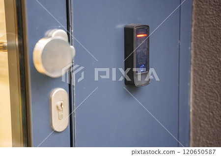 Close up view of door with electric lock with reader of entry system mounted on a house wall 120650587