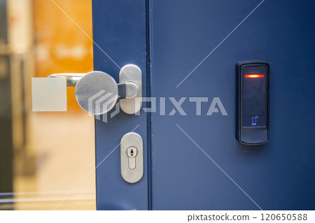 Close up view of door with electric lock with reader of entry system mounted on a house wall 120650588