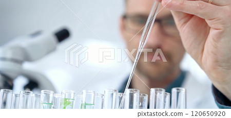 Man researcher with safety glasses is working with lab tubes using a pipette in laboratory, close-up of lab equipment. Science and medicine 120650920