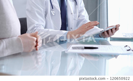 Doctor is consulting patient in modern clinic. Healthcare professional discusses medical information with a woman, using a tablet computer. Medicine concept Doctor is consulting patient in modern clinic. Healthcare professional discusses medical information with a woman, using a tablet computer. Medicine concept 120650922