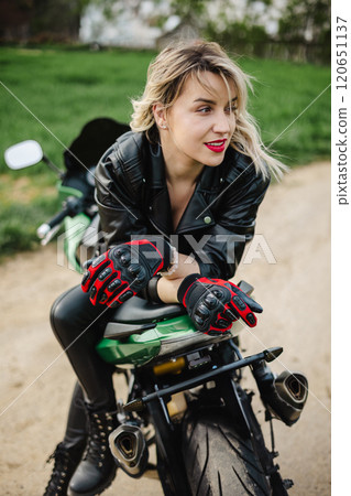Woman on Motorcycle in Leather Jacket. Stylish woman sits on a motorcycle, dressed in black leather Woman on Motorcycle in Leather Jacket. Stylish woman sits on a motorcycle, dressed in black leather 120651137