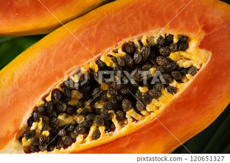Juicy papaya slices top view showcase this vitamin rich fruit. Tropical papaya fruit cut in half, with seeds and bright orange flesh displayed. 120651327