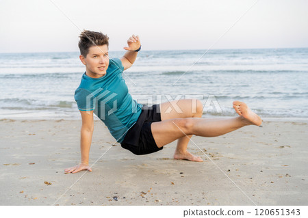 Sporty woman is engaged in animal flow gymnastics outdoors on sea beach. Female trains with Animal Flow workout to elevate her body weight workout. Innovative animal instinct fitness sport movement. Sporty woman is engaged in animal flow gymnastics outdoors on sea beach. Female trains with Animal Flow workout to elevate her body weight workout. Innovative animal instinct fitness sport movement. 120651343