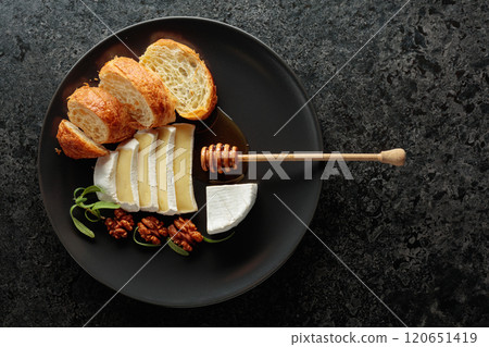 Camembert cream cheese with honey, croissants, and walnuts on a black plate. Camembert cream cheese with honey, croissants, and walnuts on a black plate. 120651419