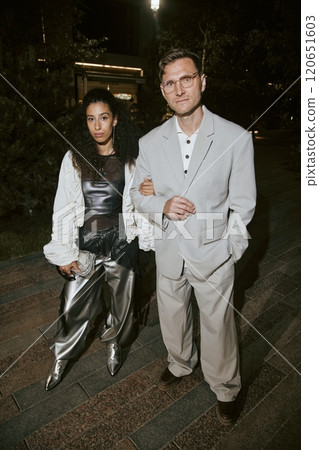 Vertical portrait shot of Middle Eastern female celebrity wearing silver outfit standing arm in arm together with mature boyfriend in gray suit while posing for paparazzi, camera flash, copy space Vertical portrait shot of Middle Eastern female celebrity wearing silver outfit standing arm in arm together with mature boyfriend in gray suit while posing for paparazzi, camera flash, copy space 120651603