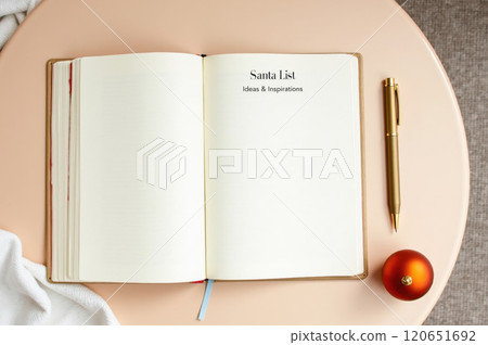 Holiday wish list on open journal with festive ornament and pen for creative ideas. AI generation 120651692