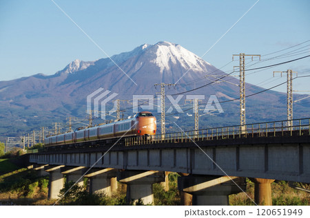 The rear view of the latest 273 series Yakumo 22 express train bound for Okayama, racing across the Hinogawa Bridge at high speed towards the foot of Mt. Oyama, covered in its first snowfall. The rear view of the latest 273 series Yakumo 22 express train bound for Okayama, racing across the Hinogawa Bridge at high speed towards the foot of Mt. Oyama, covered in its first snowfall. 120651949
