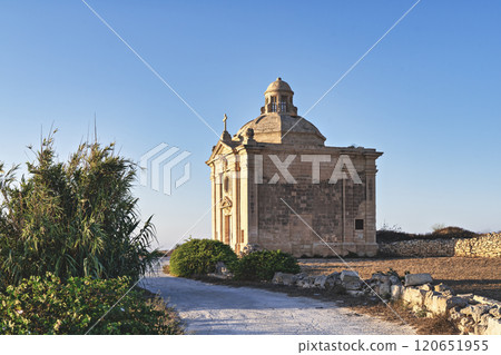 Side view of chapel of Saint Nicholas surrounded by greenery in tranquil rural Mediterranean setting under clear blue sky 120651955