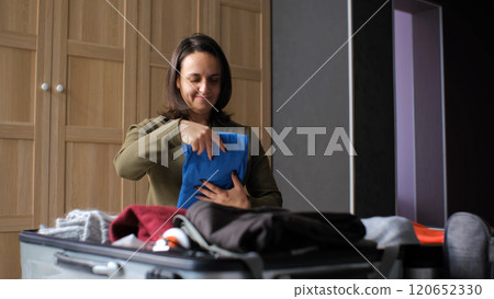 Young woman folds clothes and packs her suitcase in a cozy bedroom for an upcoming trip 120652330