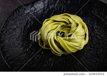 raw tagliatelle pasta, with spinach, homemade, top view, no people, on a black plate, cooking concept, raw tagliatelle pasta, with spinach, homemade, top view, no people, on a black plate, cooking concept, 120653032
