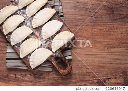 Traditional Polish dish, dumplings , raw, frozen, on a cutting board, wooden table, top view, no people, Traditional Polish dish, dumplings , raw, frozen, on a cutting board, wooden table, top view, no people, 120653047