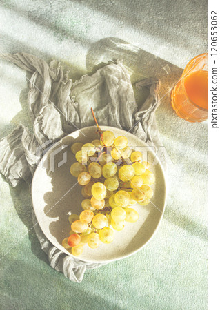 a branch of white grapes, on a gray plate, with a glass of white wine, top view, natural light, food concept, no people, 120653062