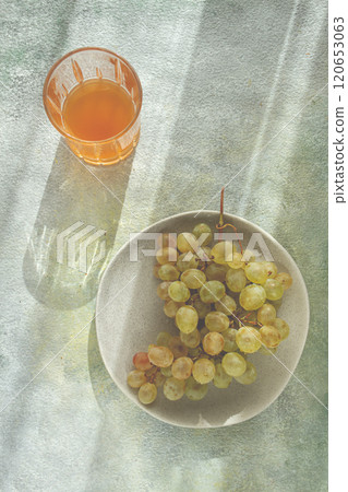 a branch of white grapes, on a gray plate, with a glass of white wine, top view, natural light, food concept, no people, 120653063