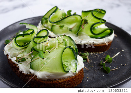 Breakfast, grain bread sandwiches, cream cheese, sliced cucumber, with microgreens, and sesame seeds, on a light table, close-up, top view, selective focus, no people, 120653211