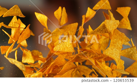 Freeze motion of flying fried tortilla nachos chips on gradient yellow background Freeze motion of flying fried tortilla nachos chips on gradient yellow background 120653539
