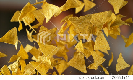 Freeze motion of flying fried tortilla nachos chips on gradient yellow background 120653545