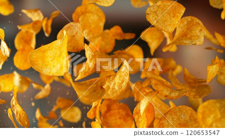 Freeze motion of flying fried potatoes chips on gradient yellow background Freeze motion of flying fried potatoes chips on gradient yellow background 120653547