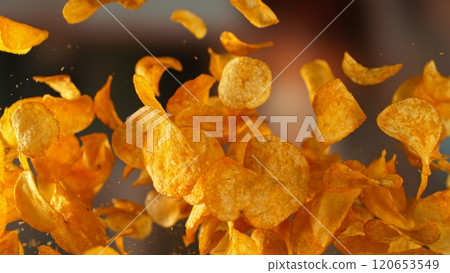Freeze motion of flying fried potatoes chips on gradient yellow background 120653549