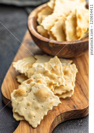 A crispy salted crackers on cutting board on black table. A crispy salted crackers on cutting board on black table. 120654411
