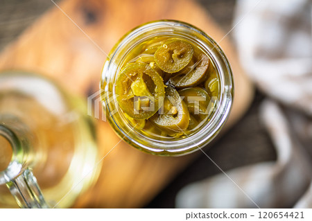 Pickled sliced jalapeno peppers in jar on wooden table. Top view. Pickled sliced jalapeno peppers in jar on wooden table. Top view. 120654421