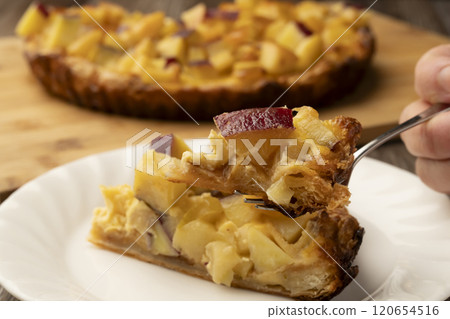 Lifting a freshly baked sweet potato and apple quiche with a fork 120654516