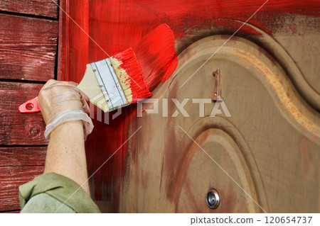 Painting front door of country house bright, rich red color with flat, wide brush. Painting front door of country house bright, rich red color with flat, wide brush. 120654737