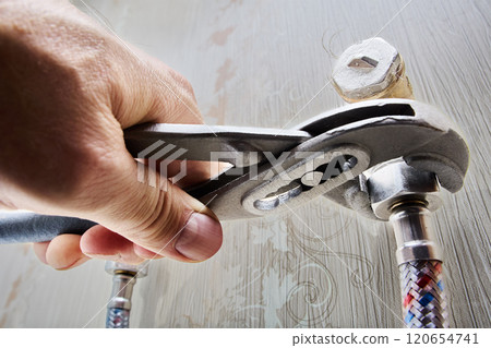 Flexible braided connecting hose is connected to elbow fitting with fastening nut is tightened using adjustable wrench pliers. 120654741