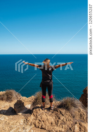 Girl standing on the edge of a cliff with outstretched arms Girl standing on the edge of a cliff with outstretched arms 120655287