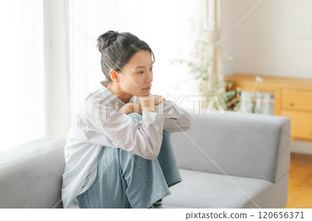 A woman in her 30s sitting on a sofa 120656371