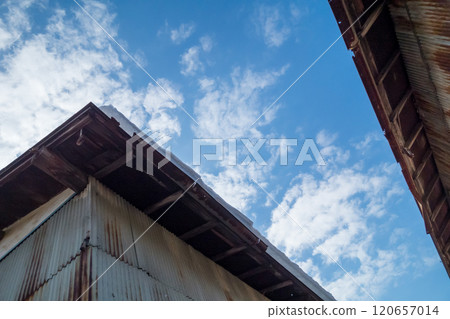 Snow piles up on the roof of a wooden, tin-roofed house 120657014