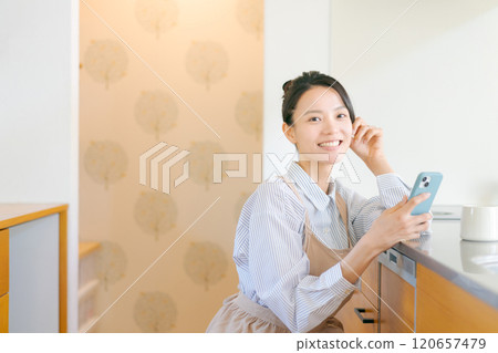 Woman using smartphone in kitchen Woman using smartphone in kitchen 120657479