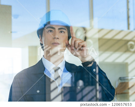 一名男工人透過大樓內的玻璃進行檢查 120657653