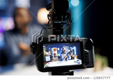 Focus on professional video production gadget used for capturing footage of internet star in blurry background filming technology reviews for niche audience, showcasing V mount battery Focus on professional video production gadget used for capturing footage of internet star in blurry background filming technology reviews for niche audience, showcasing V mount battery 120657777