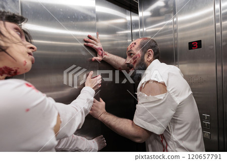 Feral ghouls stuck in office building elevator, trying to escape to infect more people and consume flesh. Spooky possessed zombies covered in bruises trapped in escalator, pulling on metallic doors 120657791
