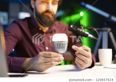 Close up shot of smart light bulb used by tech guru to teach viewers how to do maintenance. Focus on IoT home automation product held by content creator in blurry background Close up shot of smart light bulb used by tech guru to teach viewers how to do maintenance. Focus on IoT home automation product held by content creator in blurry background 120657814