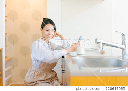 觀看一個智能手機的婦女在廚房裡 120657965