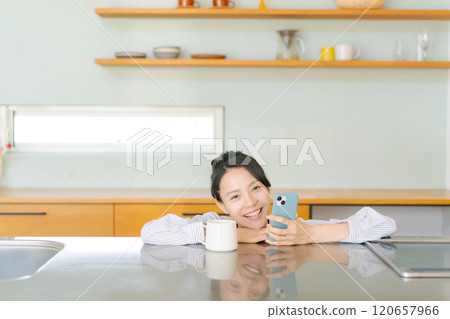 觀看一個智能手機的婦女在廚房裡 120657966