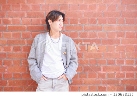 Japanese man standing in front of a brick wall Japanese man standing in front of a brick wall 120658135