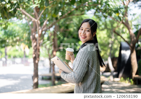 A charming, happy Asian female college student walks along the footpath on campus on a bright day. A charming, happy Asian female college student walks along the footpath on campus on a bright day. 120658190