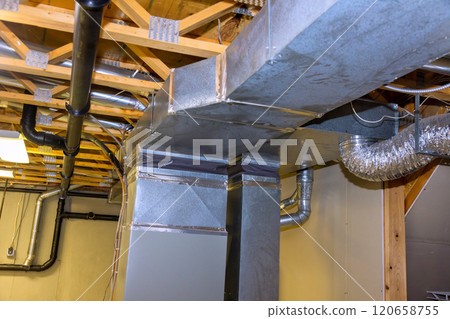 Metal ductwork is residential basement, displaying well organized HVAC system installation features various pipes, vents overhead, ensuring proper air circulation. 120658755