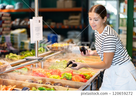 Young woman choosing eggplants in grocery store 120659272
