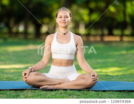 Girl meditating in lotus position during yoga session in summer park 120659366