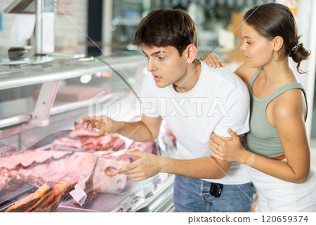Spouse near butcher shop window inspects goods and choose piece of beef for cooking rib eye steak 120659374