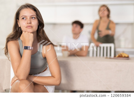Mother-in-law and son scold young daughter-in-law in home kitchen 120659384