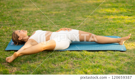 Sporty girl performing yoga asanas on green meadow in summer 120659387